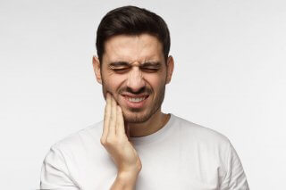 man holding his jaw in pain