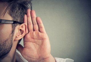 Man holding hand to his ear trying to hear better
